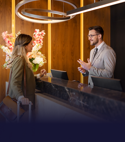 A woman checking in at the front desk of a hotel with a suited man